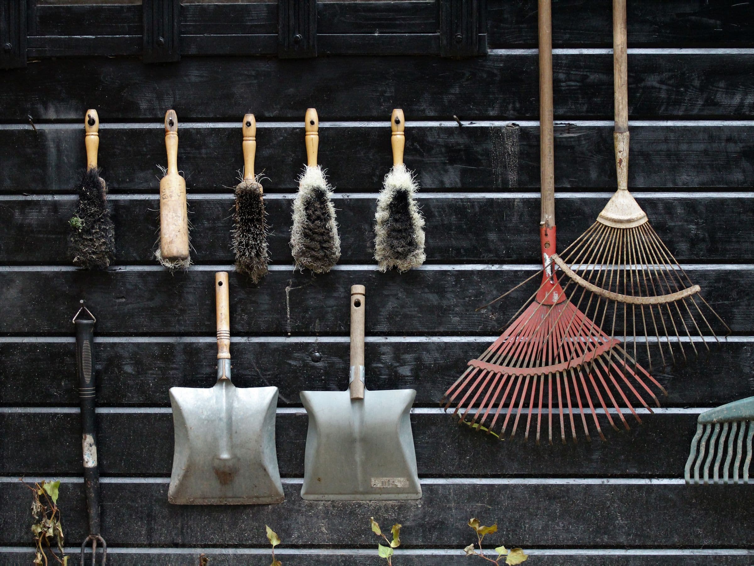 Outils de jardin suspendus à un mur en bois sombre